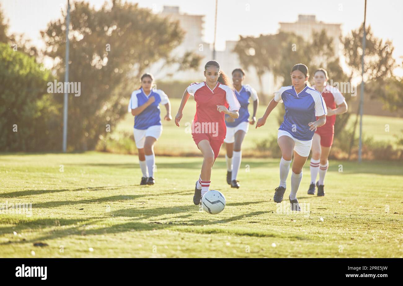 Football féminin, sport et équipe jouant sur un terrain tout en passant, touchant et courant avec un ballon. Joueurs de football actifs, rapides et qualifiés dans un jeu de compétition sur un terrain en plein air. Banque D'Images