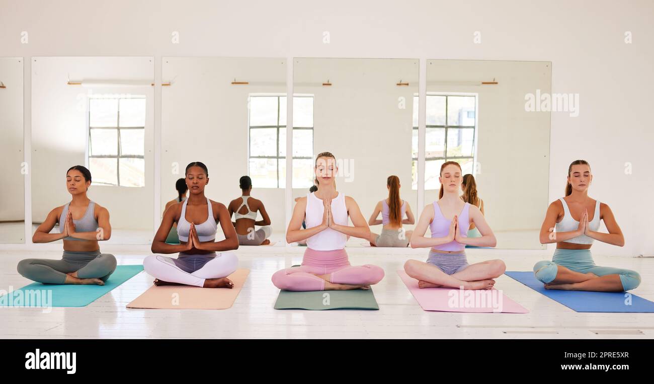 La méditation, le yoga et les amis zen classe dans le studio de pilates relaxant, sain et calme pour la respiration holistique, la santé mentale et la pleine conscience. Groupe diversifié de femmes yogi méditant dans la mudra namaste Banque D'Images