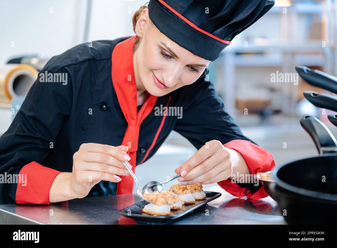 Une femme de chef assaisonnera un apéritif dans une assiette en céramique noire Banque D'Images