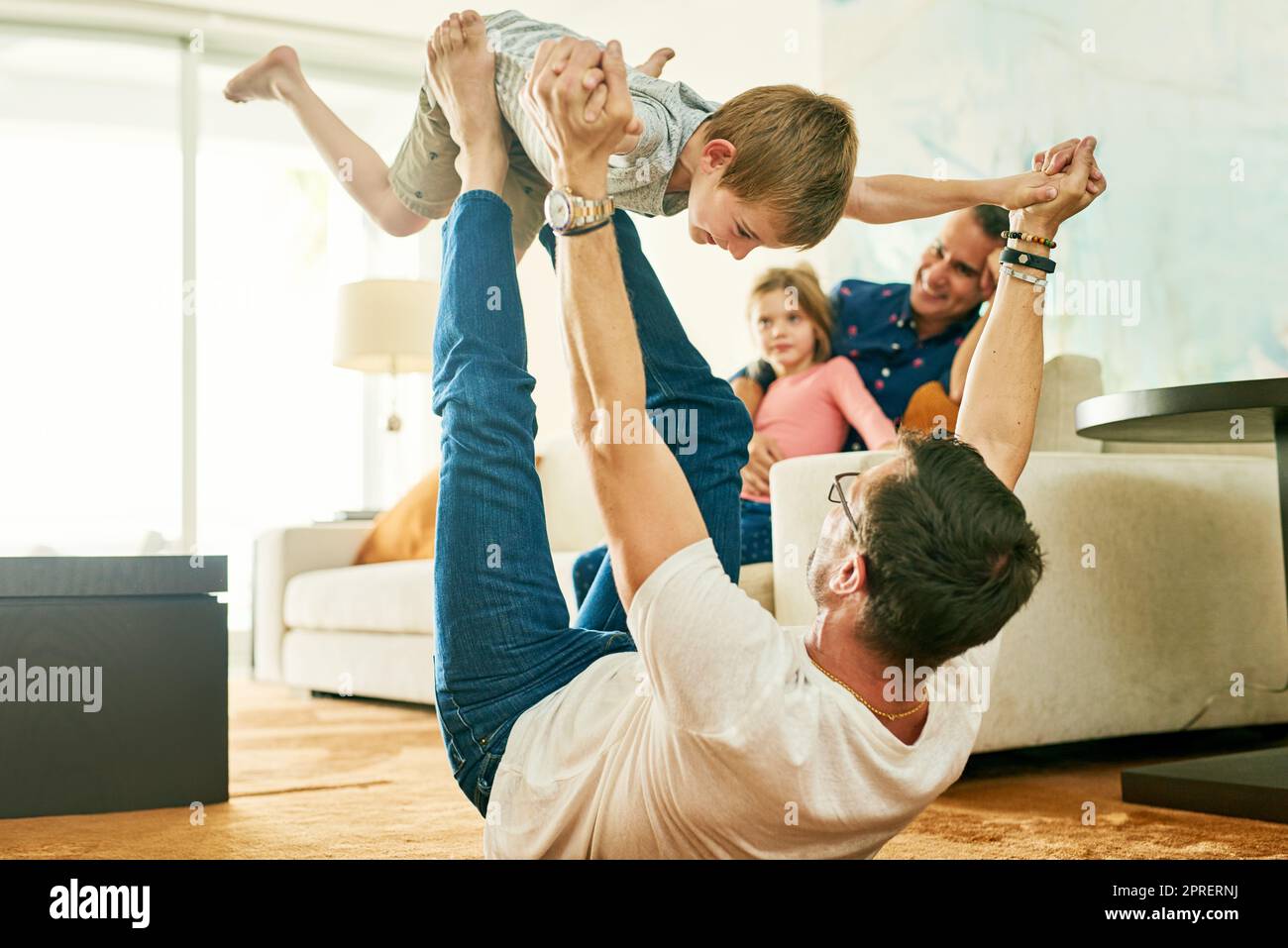 Plus haut, plus haut. Un adorable petit garçon jouant avec son père à la maison. Banque D'Images