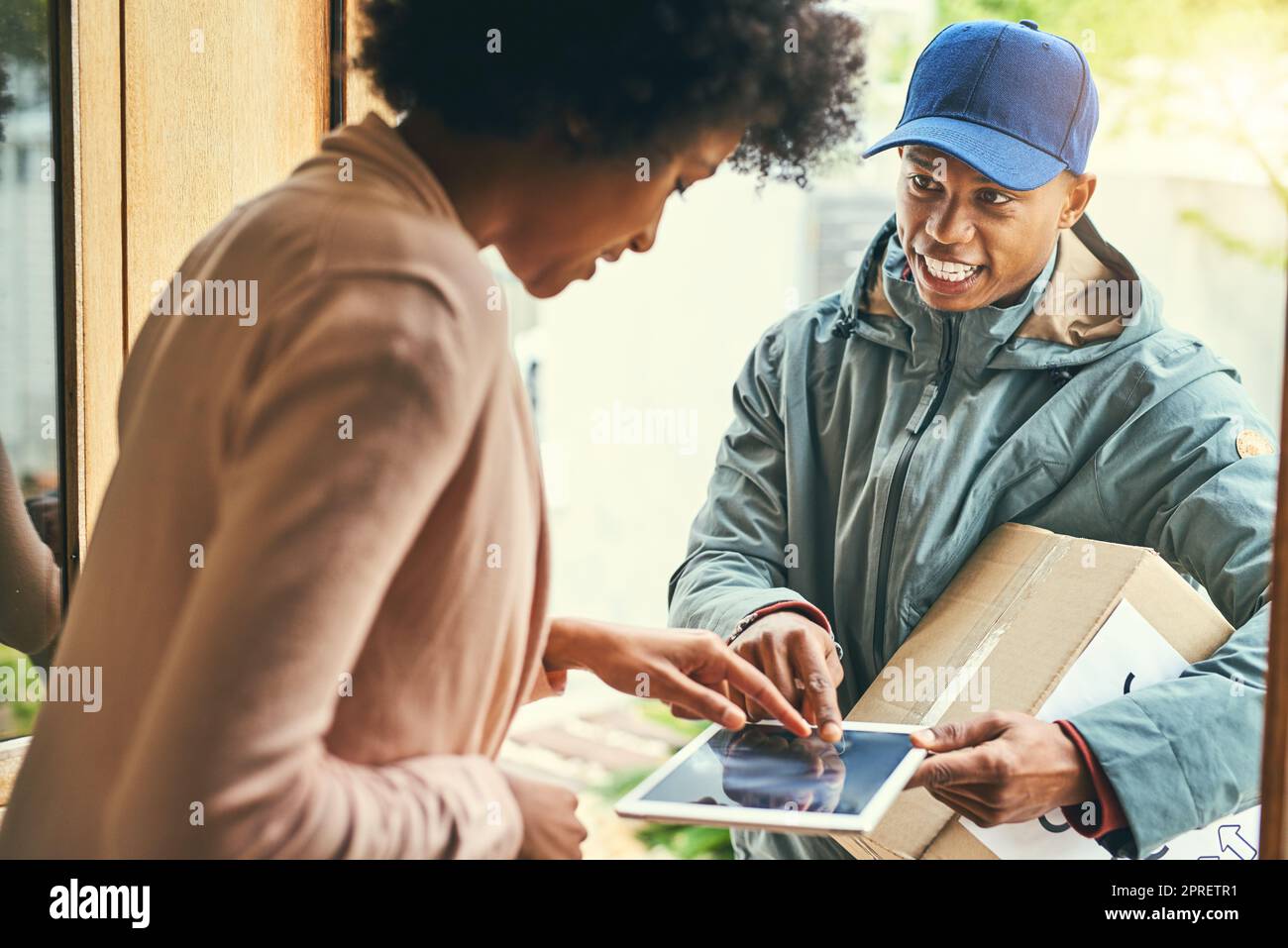 Wive a pris la voie intelligente pour faire des livraisons. Une femme utilisant une tablette numérique pour signer pour sa livraison du courrier. Banque D'Images