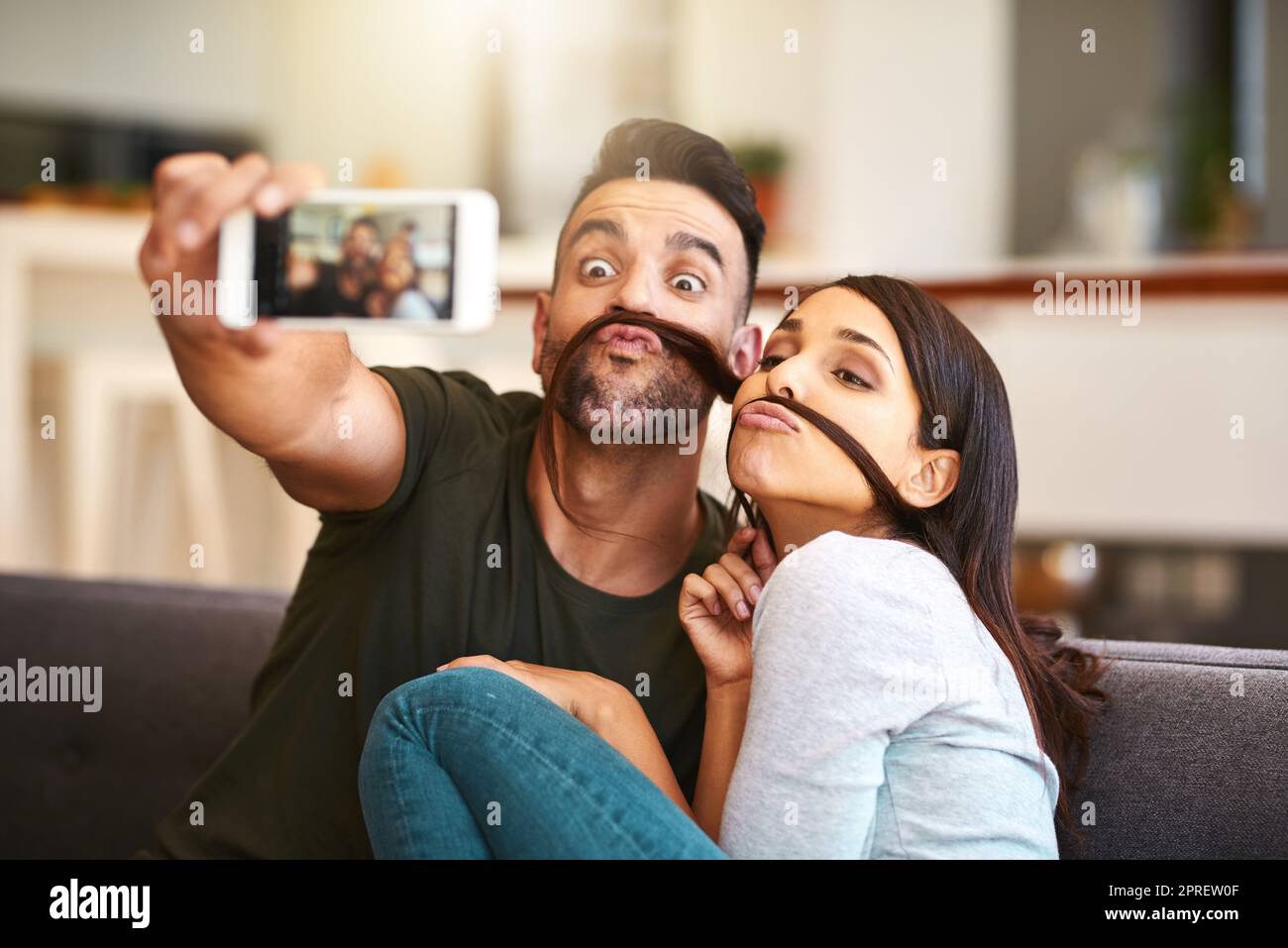 Nous sommes tombés amoureux de l'étrange l'un de l'autre. Un jeune couple prenant des selfies ensemble à la maison. Banque D'Images