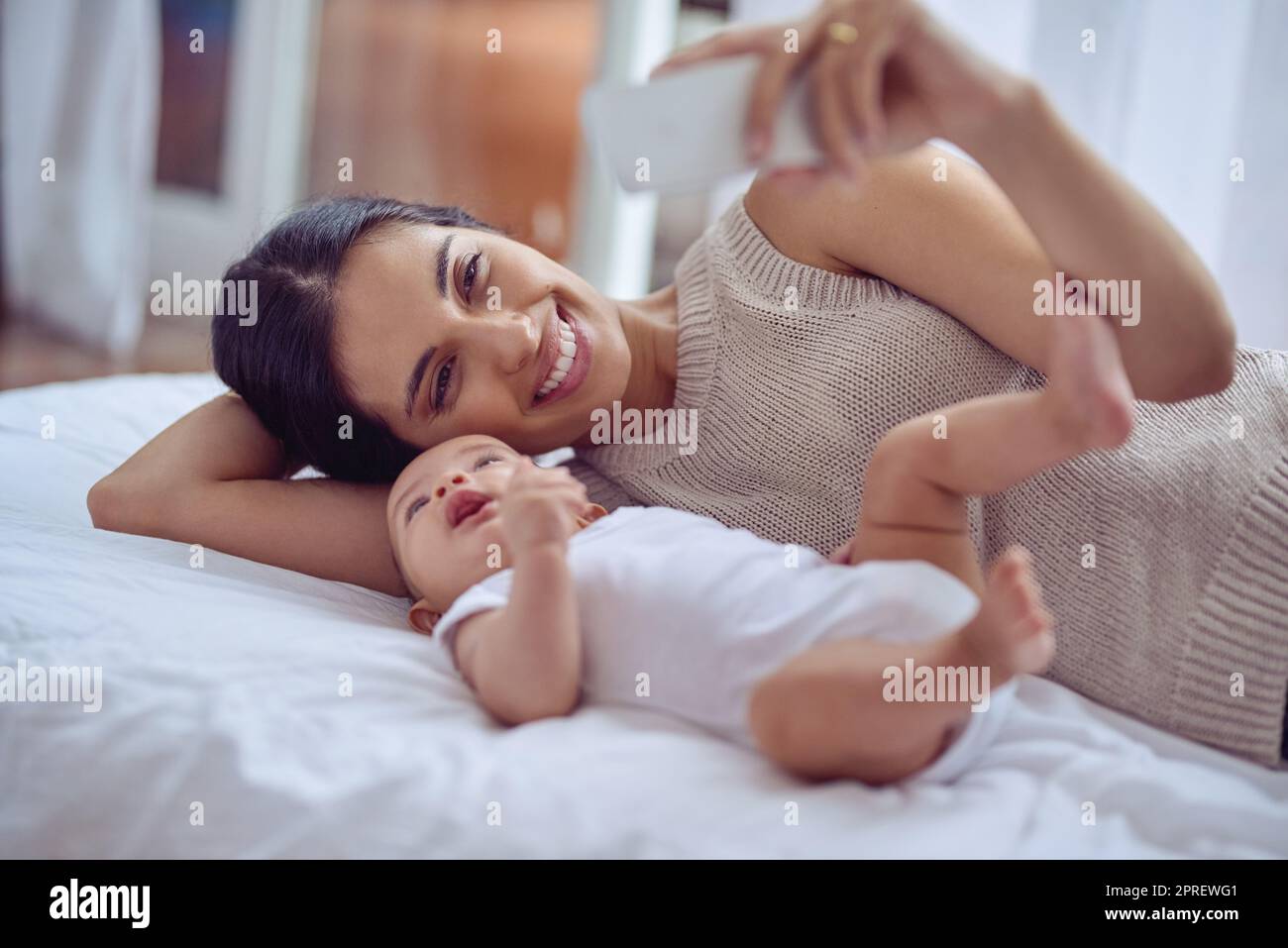 Premier selfie pour le livre de bébé. Une jeune femme prend des selfies avec son adorable bébé garçon à la maison. Banque D'Images