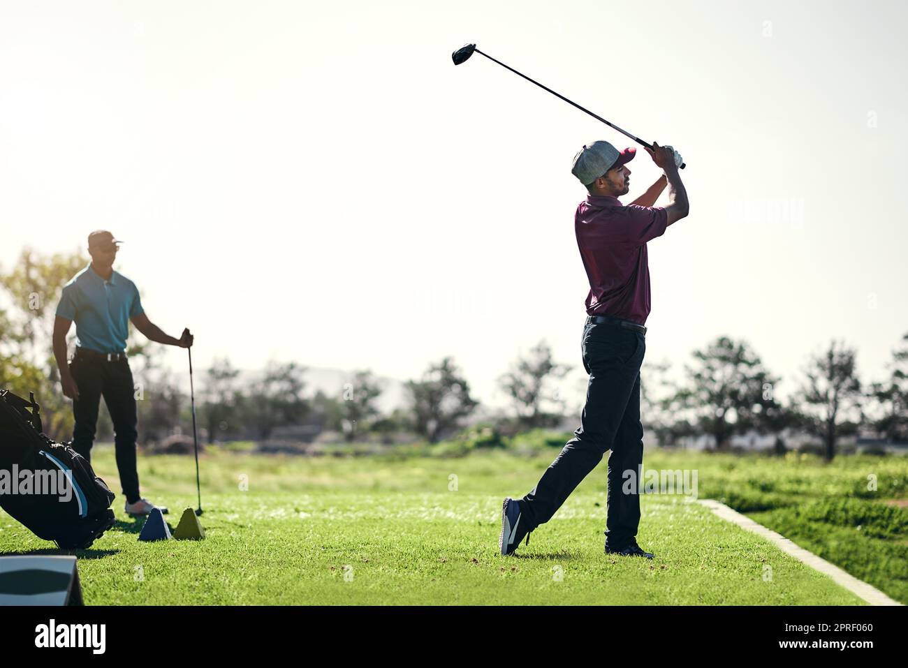 Bien joué. Un jeune golfeur masculin concentré sur le point de balancer et de jouer un tir avec son club de golf à l'extérieur sur un terrain. Banque D'Images