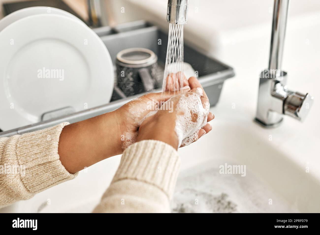 Hygiène, nettoyage et lavage des mains avec du savon et de l'eau dans l'évier de cuisine à la maison. Fermeture d'un laitage et d'un rinçage féminins pour désinfecter, protéger et prévenir la propagation du virus et des germes Banque D'Images