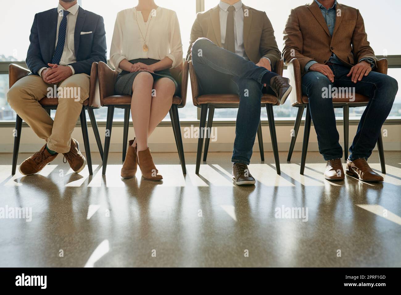 Ils attendent leur chance d'impressionner. Un groupe d'hommes d'affaires méconnus assis en file d'attente en attendant d'être interviewés. Banque D'Images