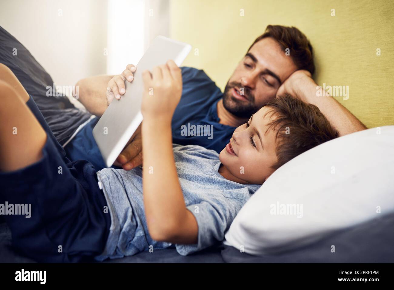 S'est connecté à un tout nouveau monde. Un jeune homme utilisant une tablette numérique avec son fils à la maison. Banque D'Images