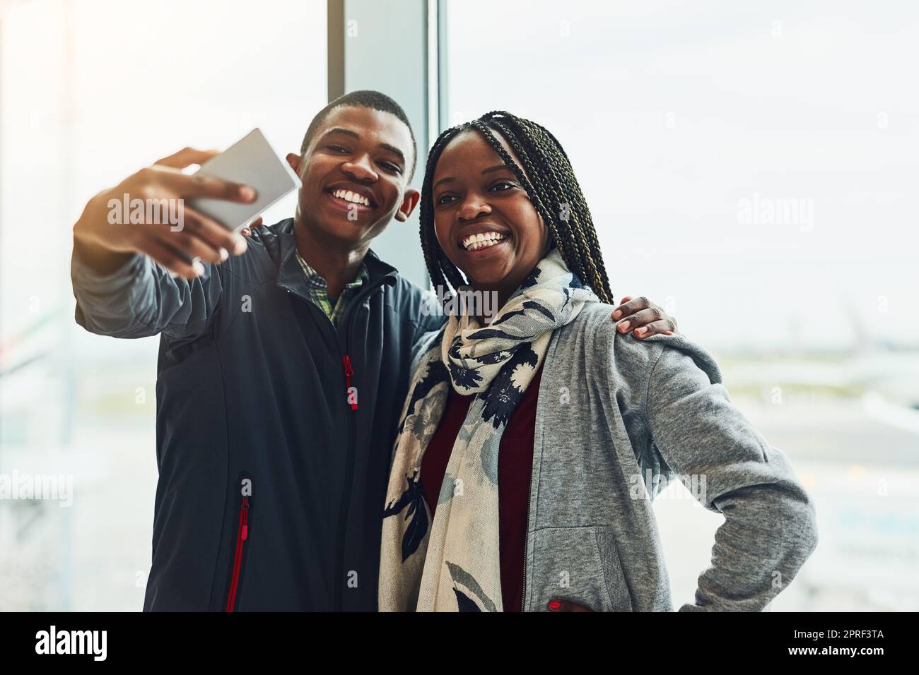 Eh bien, il faut tout documenter sur notre voyage. Deux jeunes qui prennent un selfie ensemble à l'aéroport. Banque D'Images