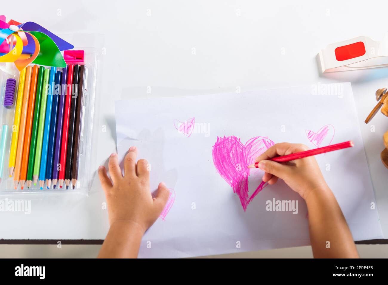 Joyeux enfant petite fille coloré dessin coeur rose sur papier blanc Banque D'Images