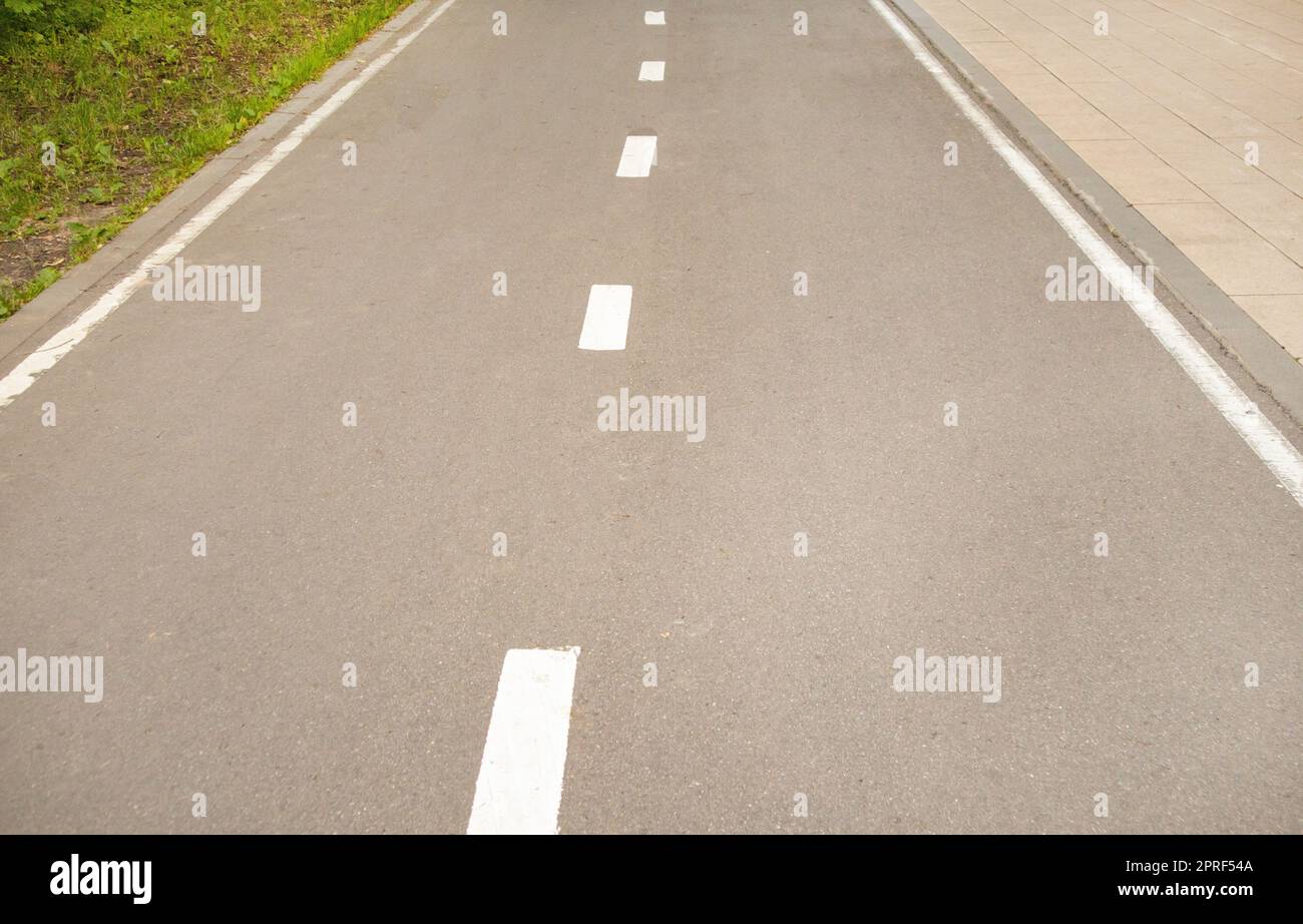 Gros plan d'une route asphaltée avec une ligne de marquage intermittente et de l'herbe sur le côté de la route. Mise au point sélective, photographie en noir et blanc Banque D'Images