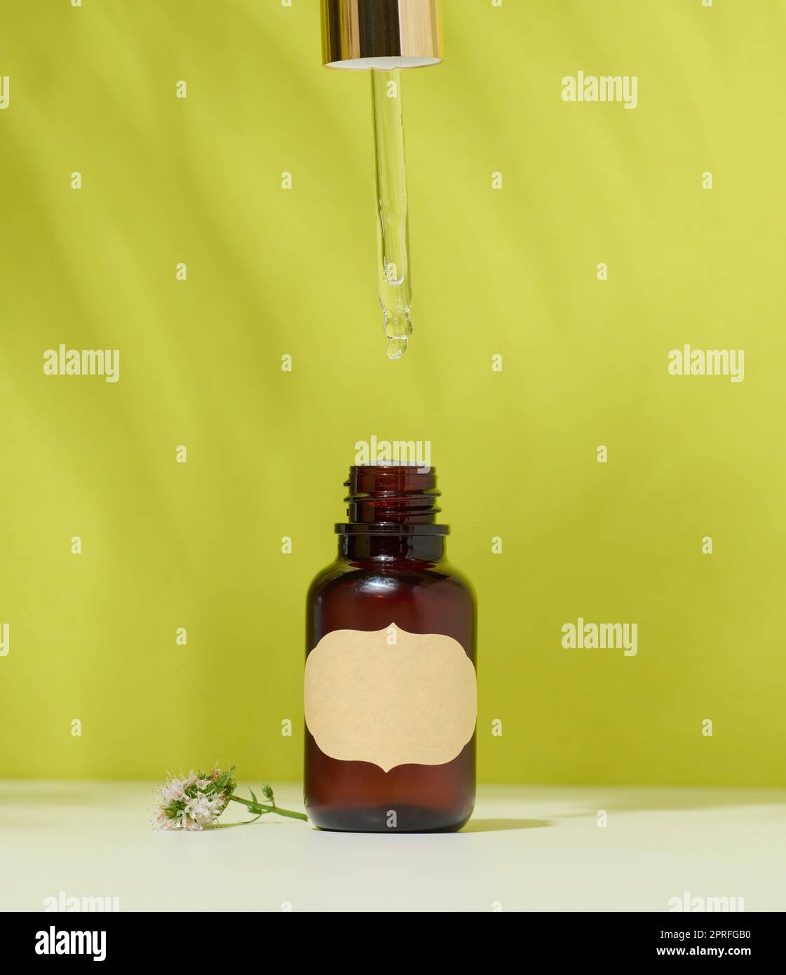 Bouteille en verre brun avec un produit cosmétique et une pipette, fond vert. Récipient pour huiles Banque D'Images