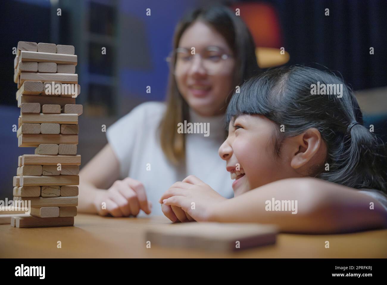 Femme souriante aider à enseigner le jeu d'enfant construire constructeur de blocs de bois, jeune mère asiatique jouant le jeu dans le bloc de bois avec sa petite fille à la maison Banque D'Images