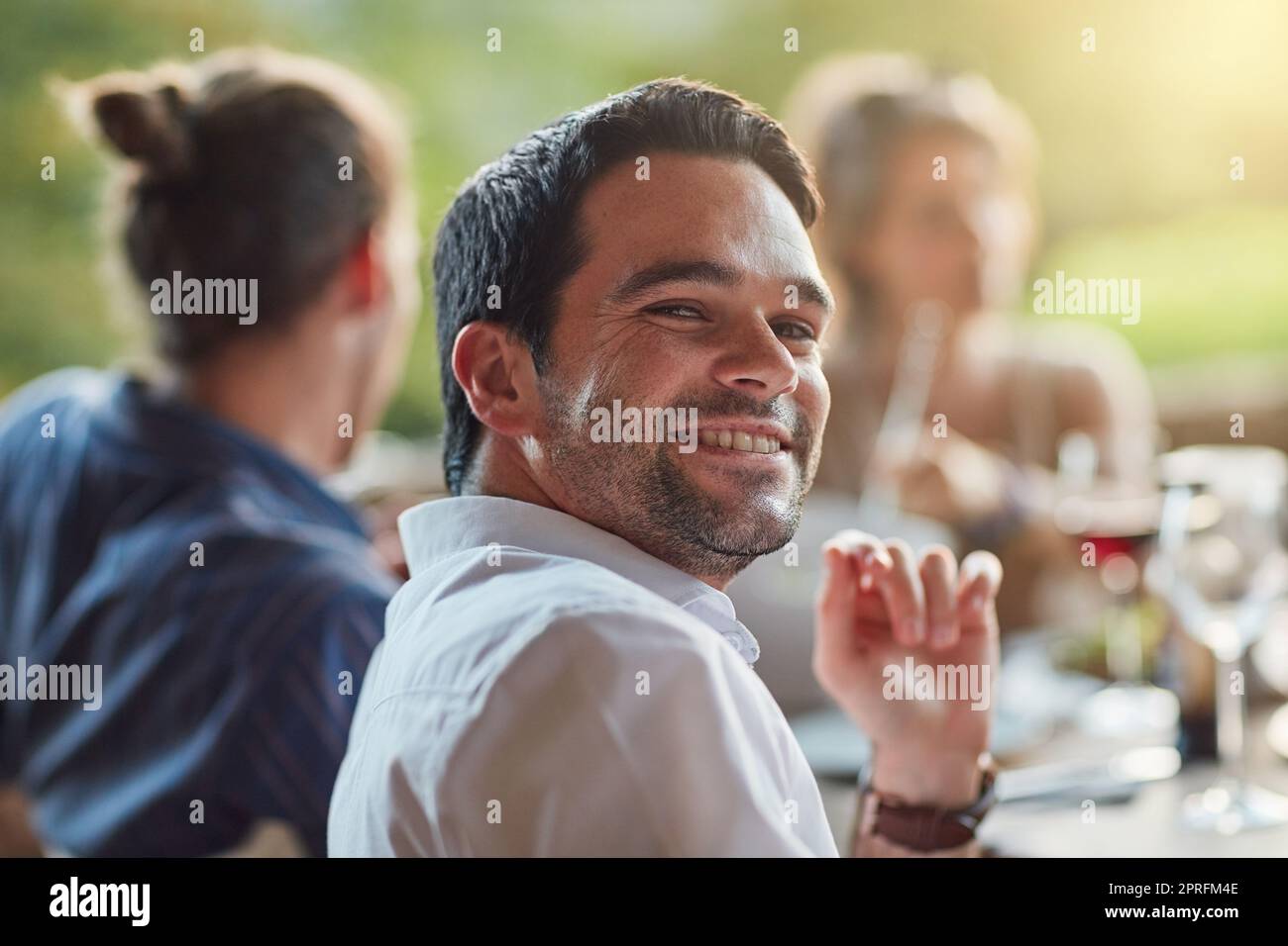 La messagerie instantanée est la plus heureuse lorsque j'ai des messages instantanés avec mes amis. Portrait d'un jeune homme heureux partageant un repas avec des amis lors d'un dîner en plein air. Banque D'Images