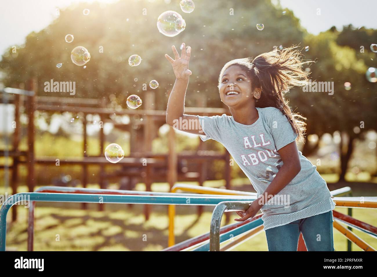 Je dois tous les attraper avant qu'ils ne surgent. Une adorable petite fille jouant avec des bulles dans le parc. Banque D'Images