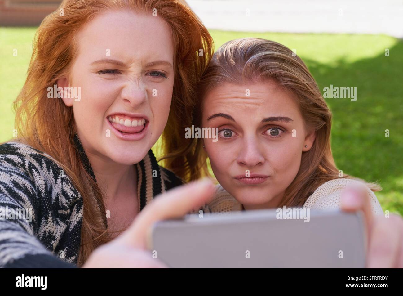 Les meilleurs amis sont des gens qui sont votre genre de fou. Deux jeunes amis prenant un selfie avec un téléphone. Banque D'Images