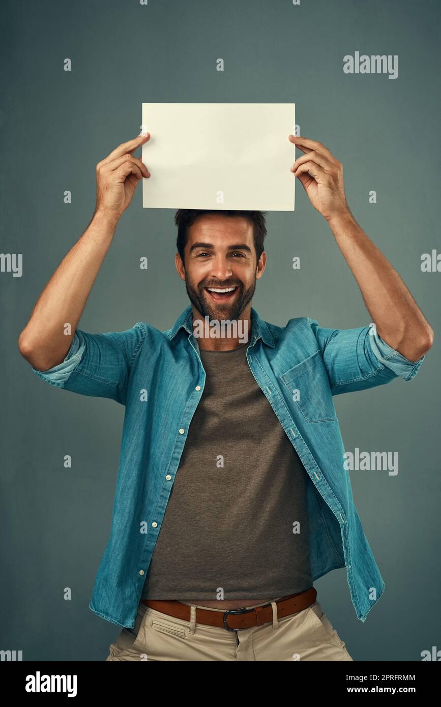 IVE a enregistré cet espace pour vous. Portrait studio d'un jeune homme beau tenant une pancarte vierge sur fond gris. Banque D'Images