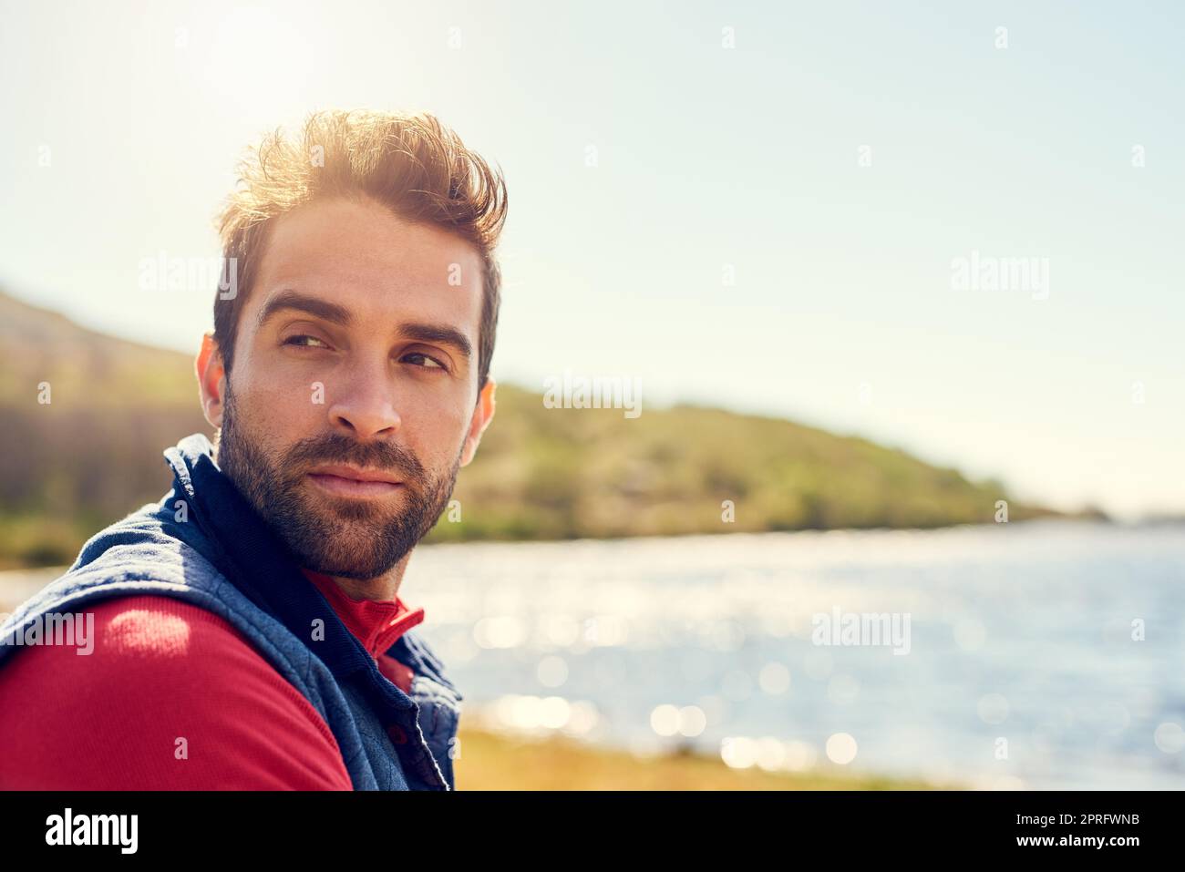Recueillant ses pensées dans la nature. Un randonneur attentionné qui admirait la vue sur un lac par une journée ensoleillée. Banque D'Images