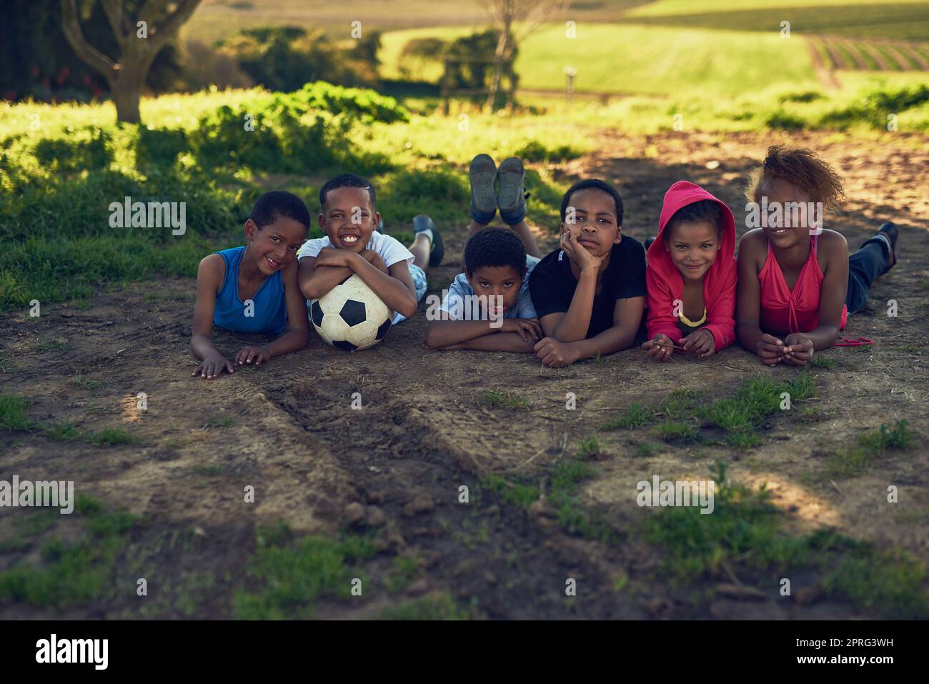 Footballeurs en préparation. Un groupe d'enfants allongé avec un ballon de football sur un peu d'herbe dehors. Banque D'Images