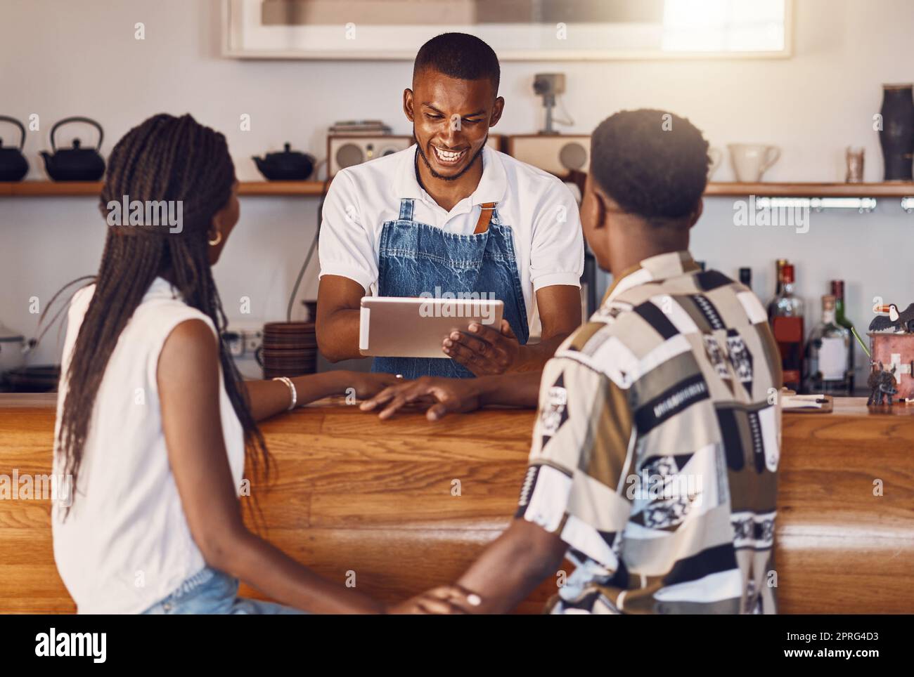 Hospitalité, service et technologie avec un employé de restaurant prenant des commandes sur une tablette numérique, souriant et parlant. Les jeunes employés gèrent le paiement client sur une application en ligne, en payant via Internet Banque D'Images