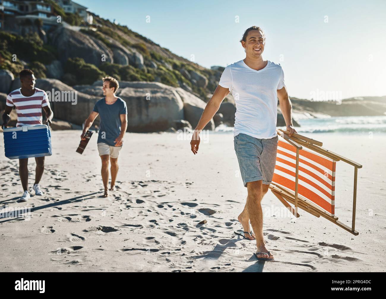 C'est parti pour la journée de la plage. Un groupe de jeunes amis qui marchent sur la plage par une journée ensoleillée. Banque D'Images
