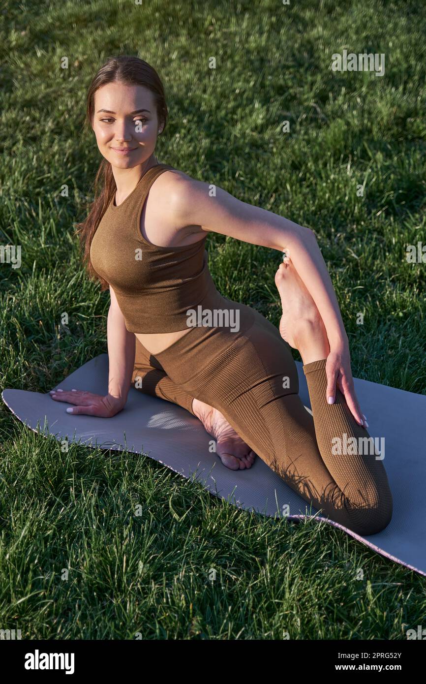 Jeune belle femme avec le corps athlétique fait du yoga dans le parc. Banque D'Images