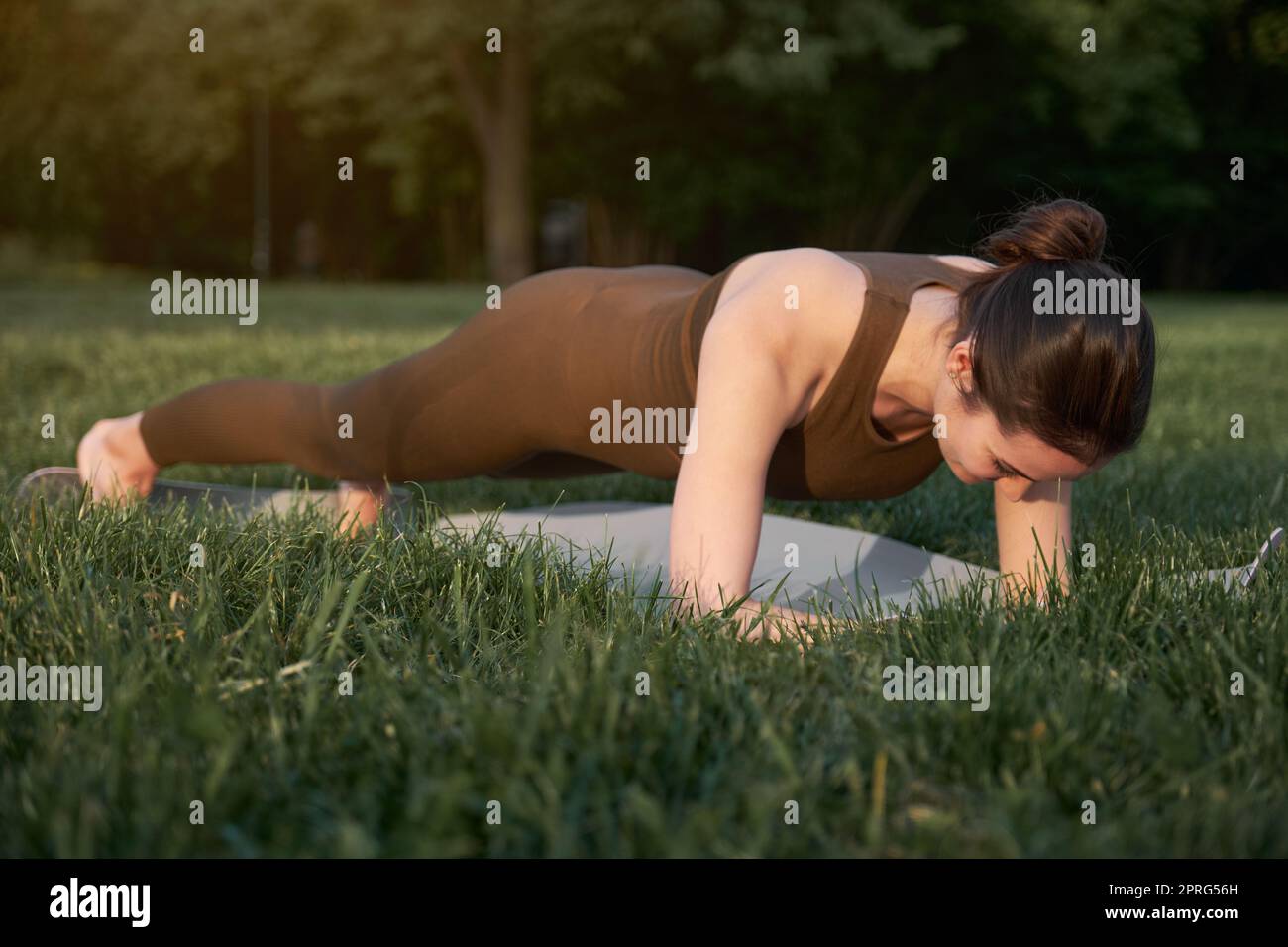 Femme athlétique faisant du yoga dans le parc en se tenant debout dans une position de planche. Banque D'Images