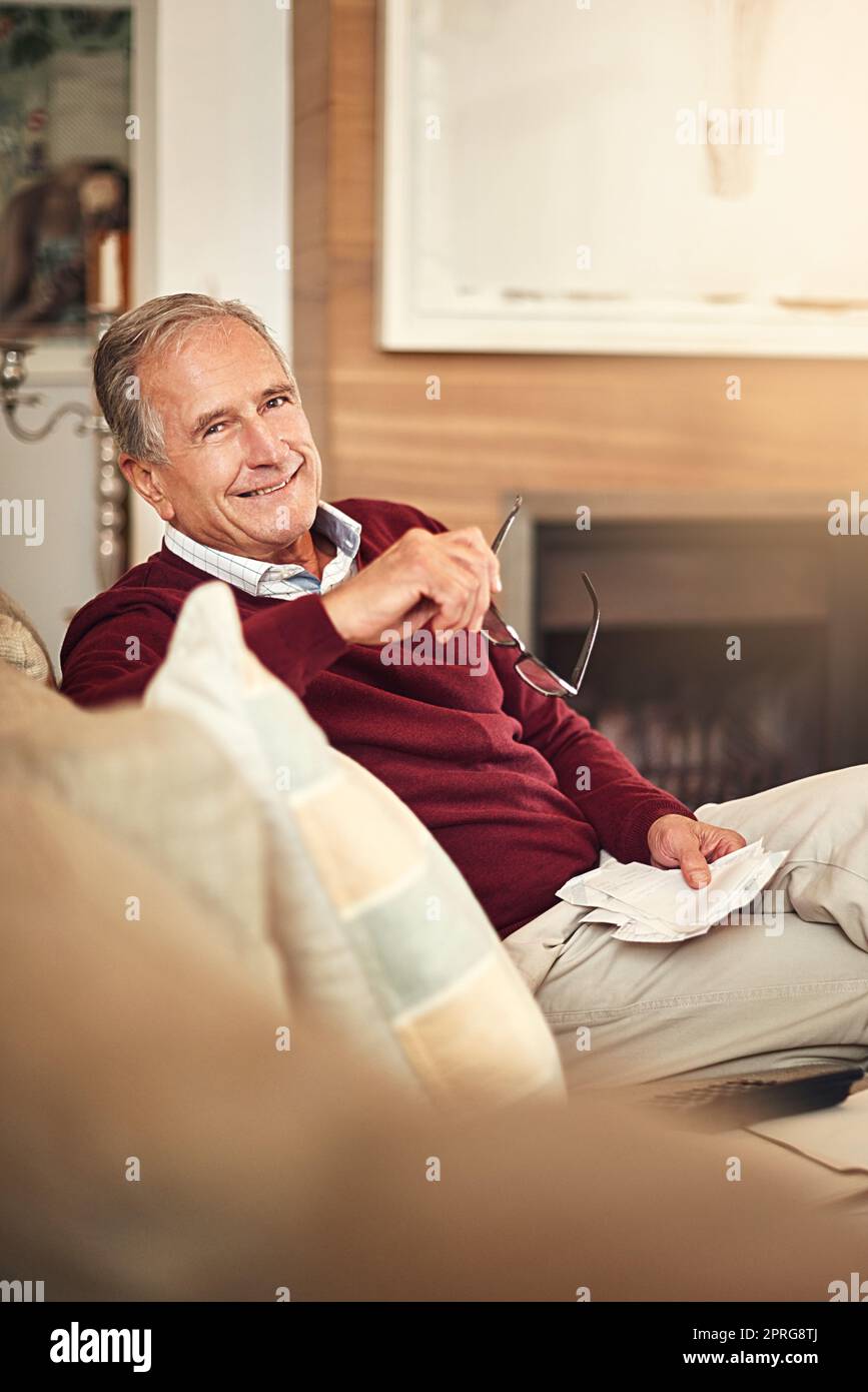 Ces remises senior s'ajoutent vraiment. Portrait d'un homme senior assis à la maison en tenant des reçus. Banque D'Images