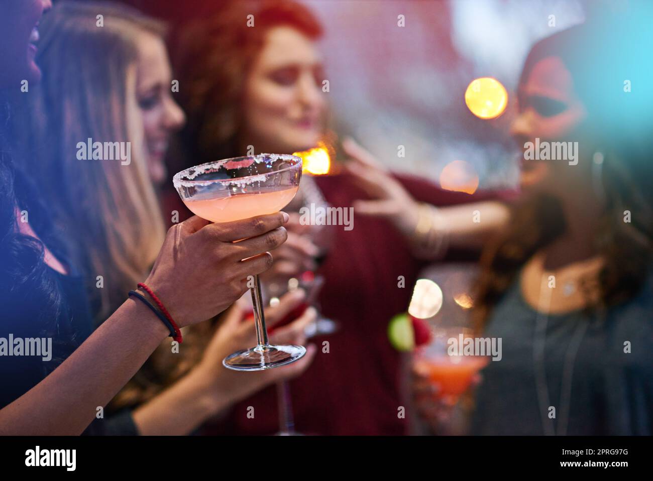 Dans une ambiance festive. Un groupe de jeunes femmes qui boivent des cocktails lors d'une fête. Banque D'Images