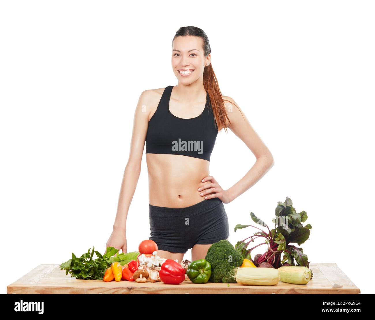 Votre corps vous remerciera de manger sainement. Studio portrait d'une jeune femme attrayante posant avec une table pleine de légumes sur un fond blanc. Banque D'Images