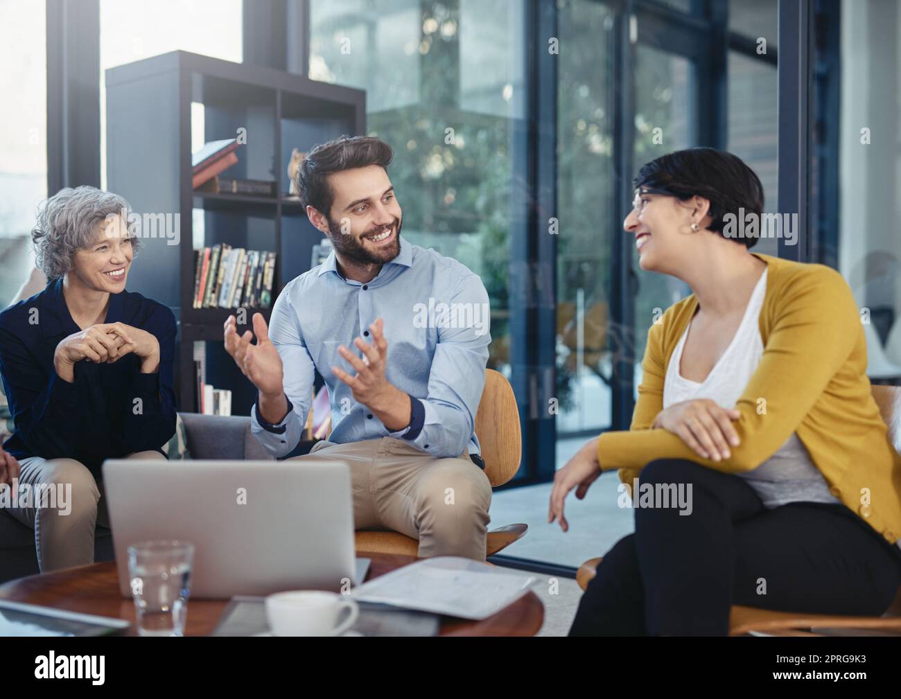 Partenaires dans la créativité. Un groupe de concepteurs travaillant sur un ordinateur portable lors d'une réunion dans un bureau. Banque D'Images