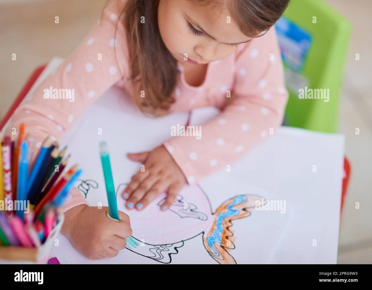 Picasso en formation. Photo en grand angle d'une petite fille colorant dans une photo à la maison. Banque D'Images