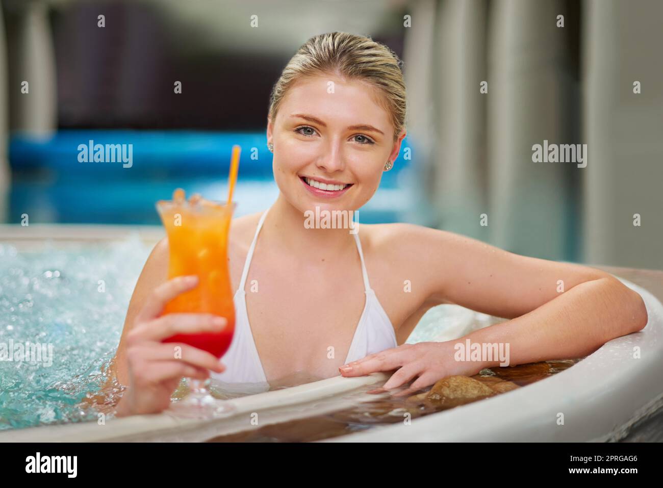 Pour une journée de luxe. Portrait d'une jeune femme qui boit un cocktail à la piscine dans un spa. Banque D'Images