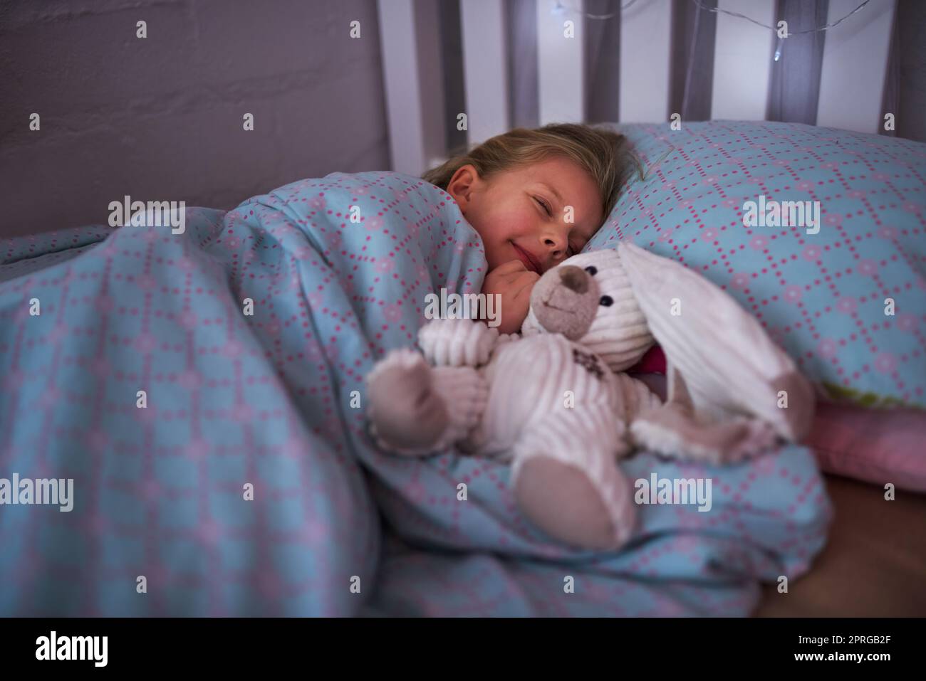 Ensuite, une petite fille dormant au lit avec son ours en peluche. Banque D'Images