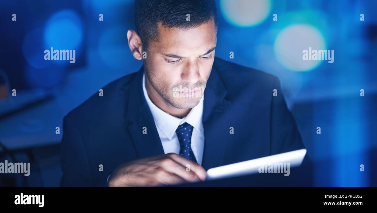 Homme d'affaires avec tablette numérique heures supplémentaires pour la recherche de données dans un bureau d'entreprise la nuit. Homme d'affaires et employé exécutif utilisant la technologie pour communiquer et établir un réseau avec une application en ligne ou un e-mail Banque D'Images