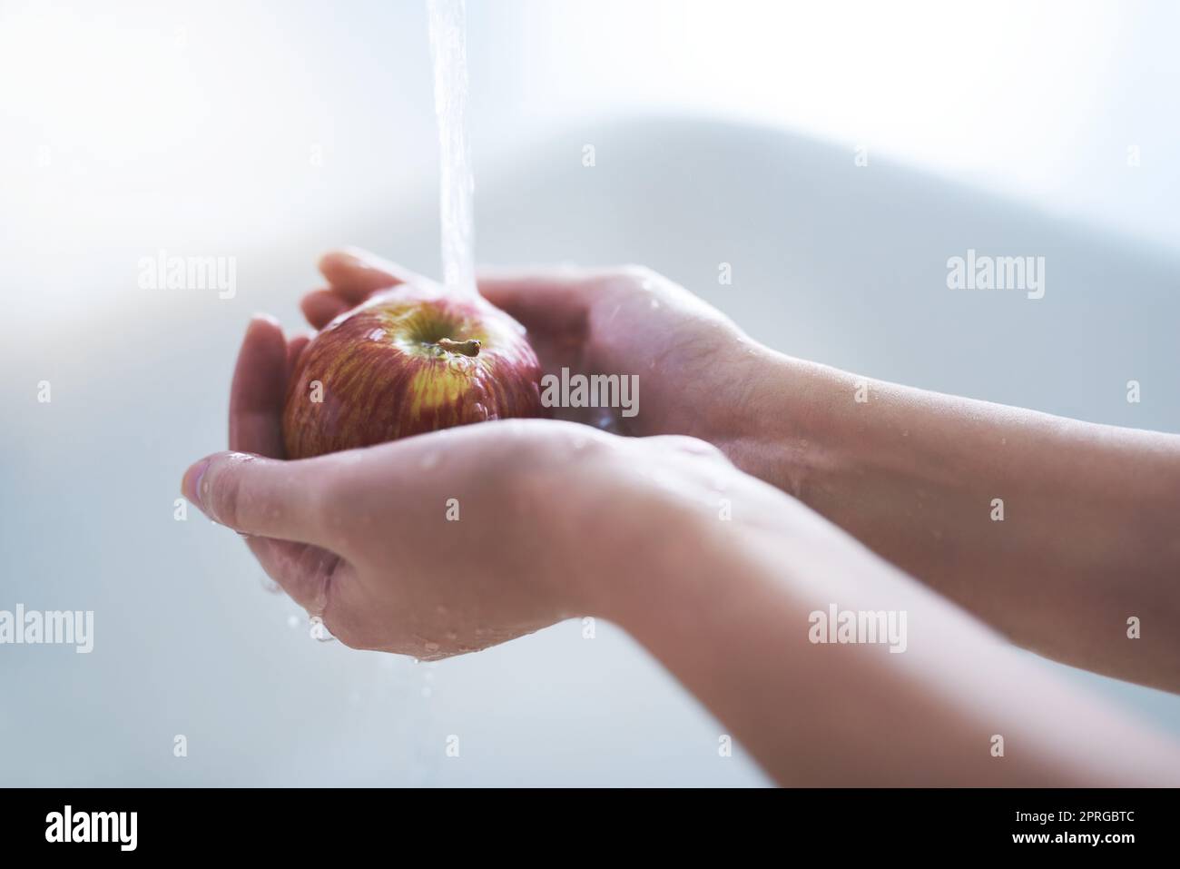 Presque prêt à manger. Une personne lavant une pomme au robinet. Banque D'Images
