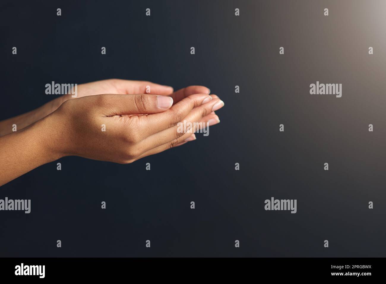 Ouvrez vos mains pour recevoir. Photo studio d'une femme méconnaissable tenant les mains ensemble sur un fond noir. Banque D'Images