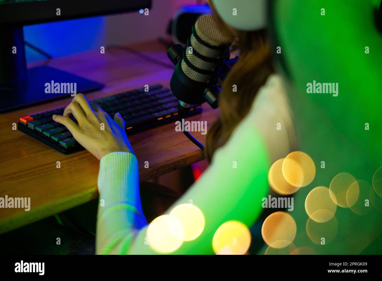 gamer femme appuyer sur le clavier pour jouer à des jeux vidéo en ligne sur l'ordinateur elle en direct et de chat avec les fans Banque D'Images