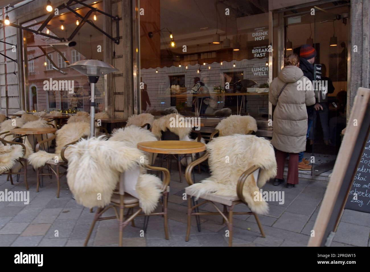 Un café dans le vieux quartier de Bratislava, Slovaquie avec des sièges couverts de peau de mouton pour les repas en plein air en hiver Banque D'Images