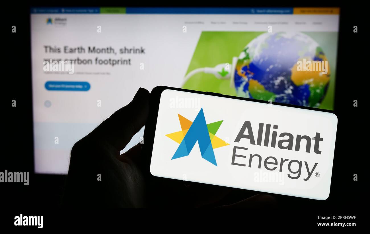 Personne tenant un smartphone avec le logo de la société américaine alliant Energy Corporation à l'écran devant le site Web. Mise au point sur l'affichage du téléphone. Banque D'Images