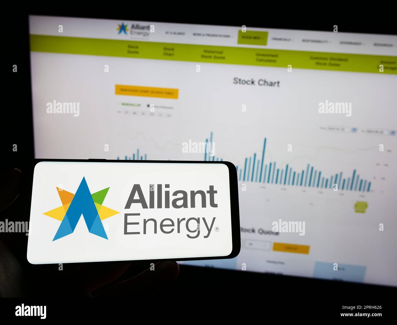 Personne tenant un téléphone portable avec le logo de la société américaine alliant Energy Corporation à l'écran en face de la page Web. Mise au point sur l'affichage du téléphone. Banque D'Images