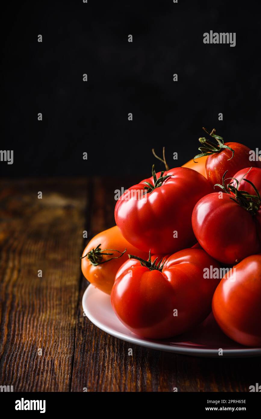 Tomates fraîches rouges et jaunes sur plaque blanche sur bois surface Banque D'Images