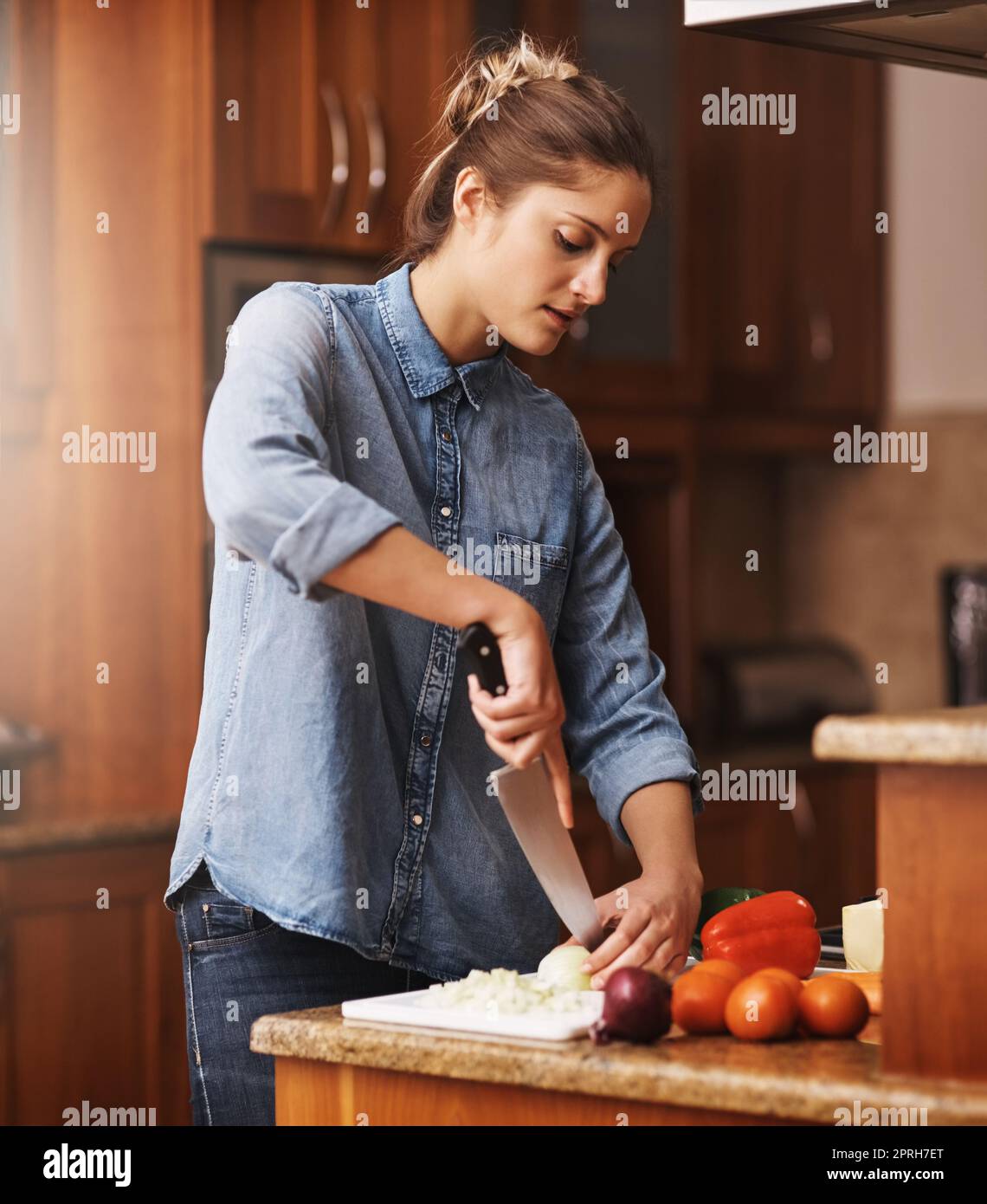 En commençant par le souper. Une jeune femme prépare un repas sain à la maison. Banque D'Images