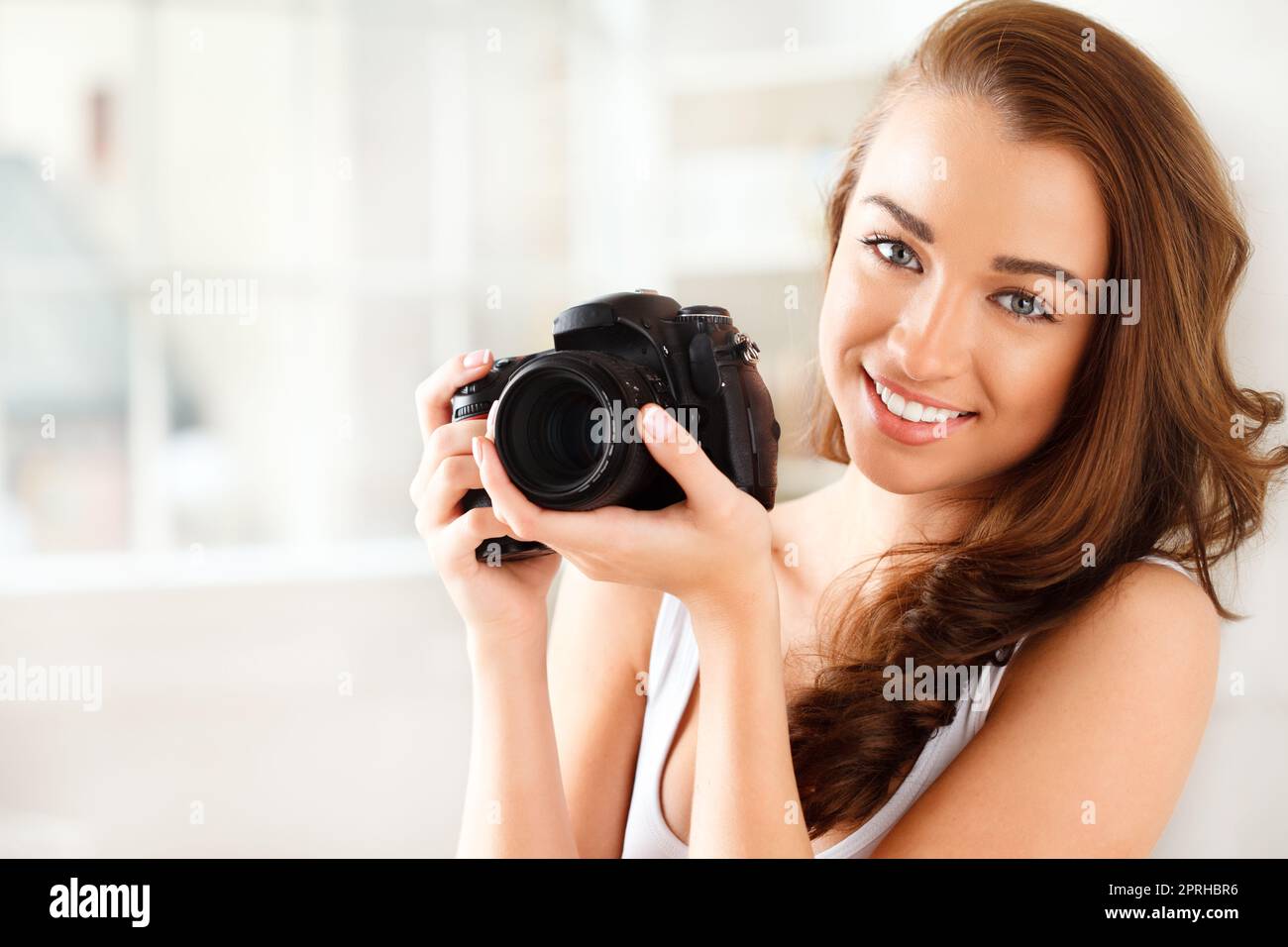 Photographe, appareil photo numérique et photographie avec une femme qui prend une photo ou une photo à l'intérieur. Portrait d'une jeune femme avec un sourire tenant le matériel photo pour une prise de vue de beauté avec un modèle heureux Banque D'Images