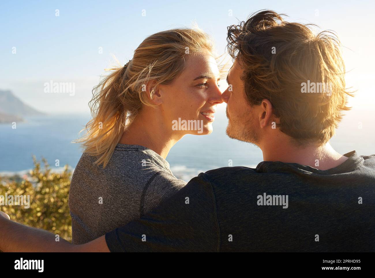 Le soleil brille et vous aussi. Un couple aimant assis sur un banc donnant sur l'océan. Banque D'Images