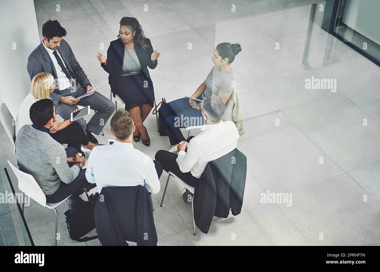 Rassembler leurs têtes pour réussir. Prise de vue en grand angle d'un groupe de collègues parlant ensemble tout en étant assis dans un cercle dans un bureau. Banque D'Images