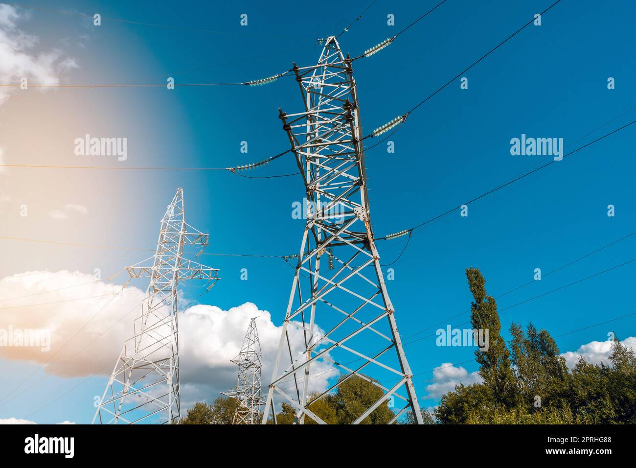 Vue à angle bas des tours haute tension et des câbles électriques contre le ciel bleu ensoleillé Banque D'Images