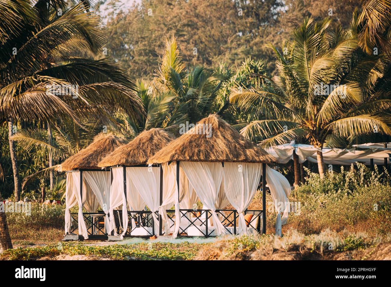 Goa, Inde. Tentes de belvédère avec toit de Strawing pour les touristes sur la plage avec tables et chaises longues à l'intérieur Banque D'Images