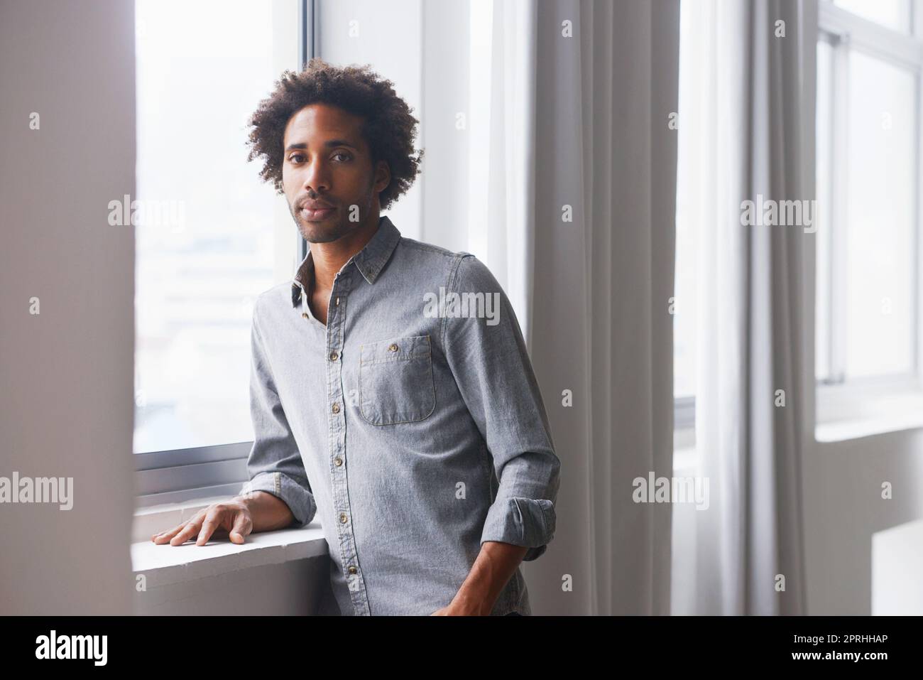 La réalisation soudaine de lundi. Un portrait d'un jeune homme sérieux penché sur un seuil de fenêtre Banque D'Images