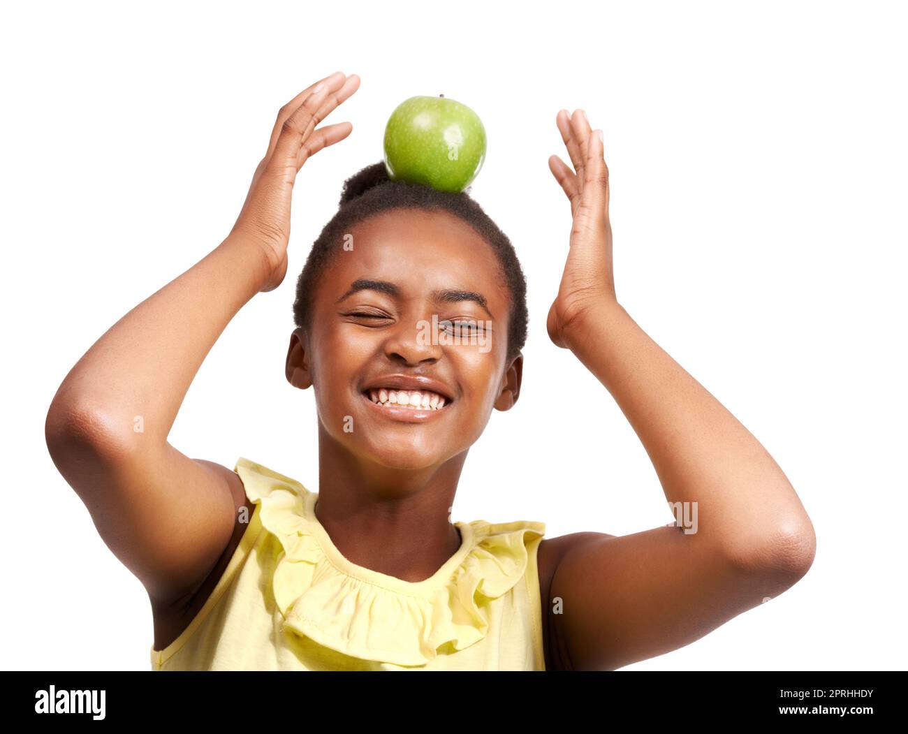 Amusez-vous avant de manger. Photo studio d'une jeune fille afro-américaine qui équilibre une pomme sur sa tête isolée sur blanc Banque D'Images