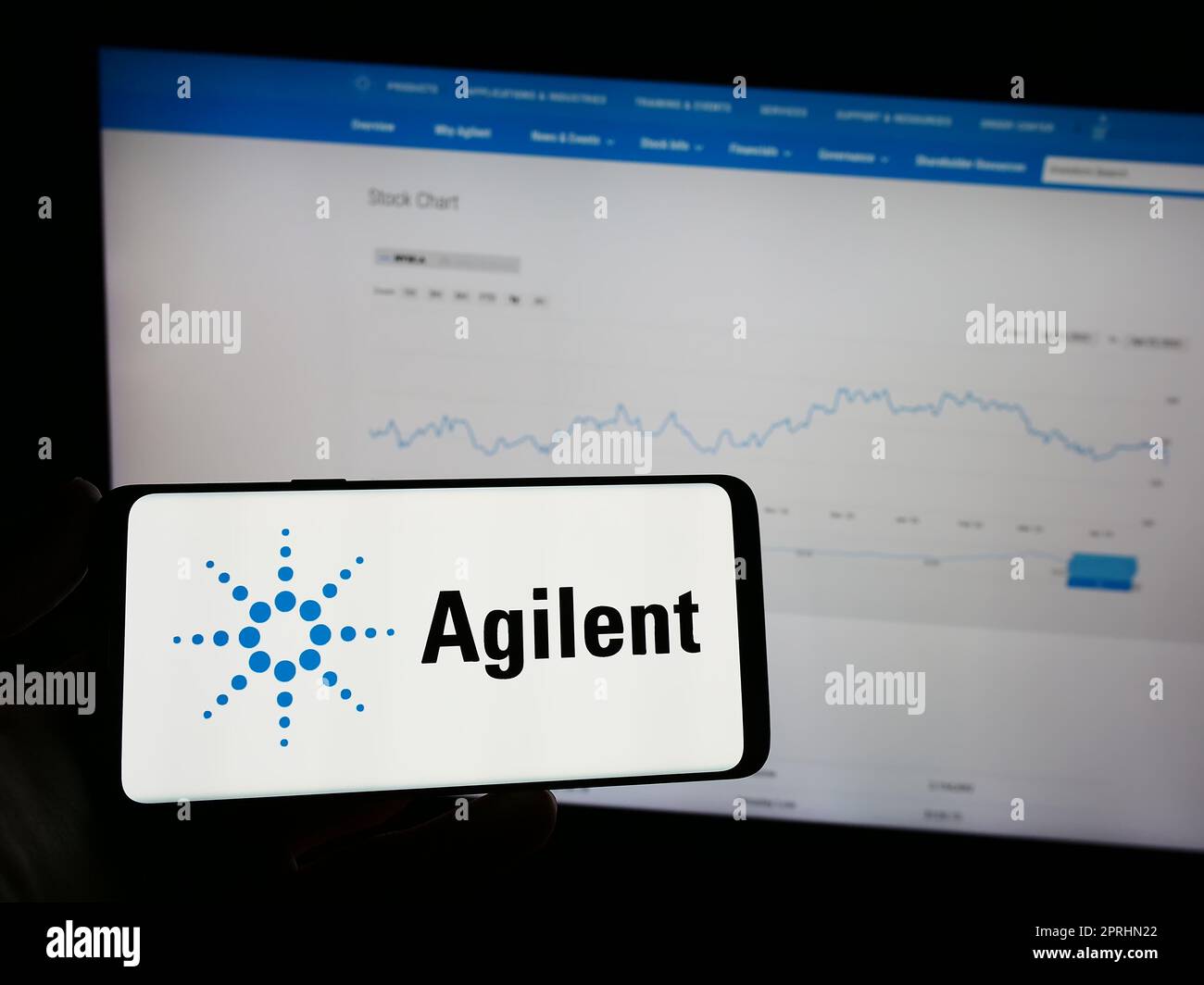 Personne tenant un téléphone portable avec le logo de la société américaine Agilent technologies Inc. À l'écran en face de la page Web. Mise au point sur l'affichage du téléphone. Banque D'Images